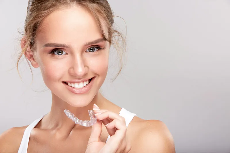 Woman holding her Invisalign clear aligners
